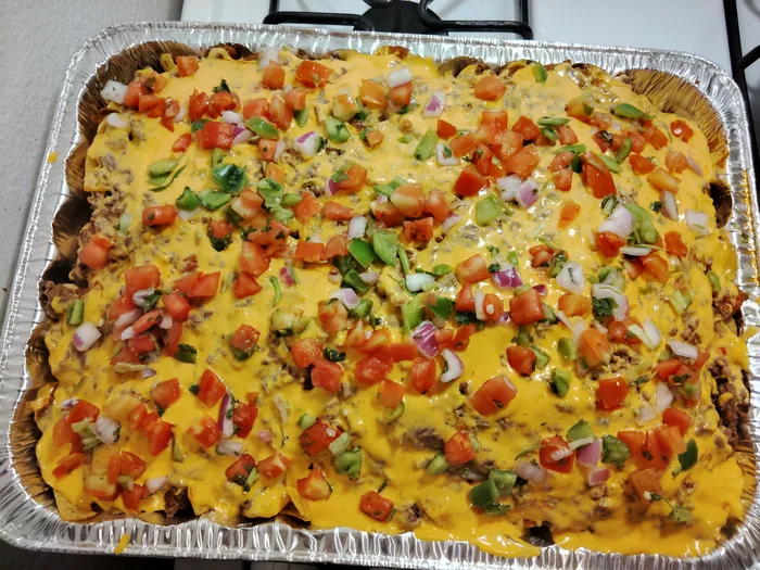 A full catering pan of baked macaroni and cheese topped with peppers