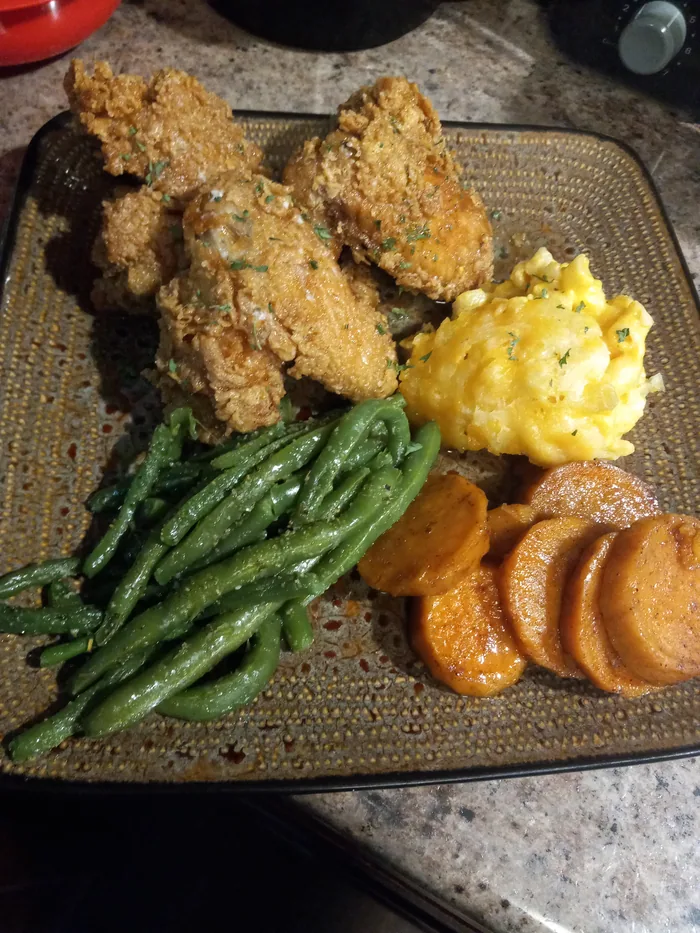 Fried chicken plated with green beans, candied sweet potatoes and a scoop of mac and cheese