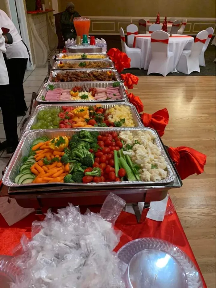 Chafing dishes and trays lined up on a buffet table for an event
