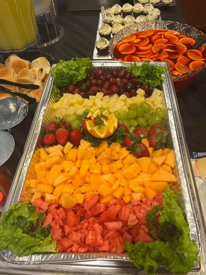 A tray of cut melon, grapes, strawberries and fresh vegetables