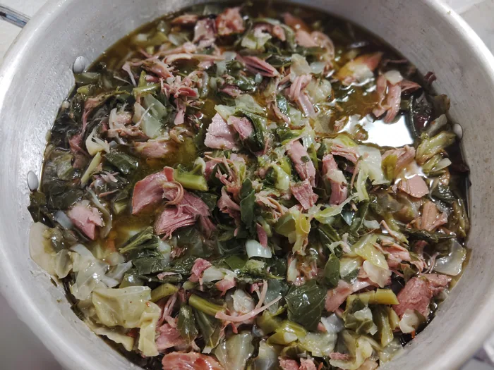 A large pot of collard greens simmering with smoked turkey