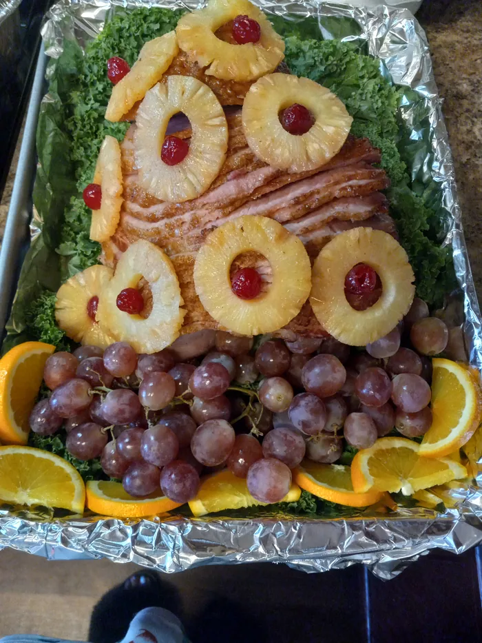 Sliced ham arranged with pineapple, grapes and orange wedges